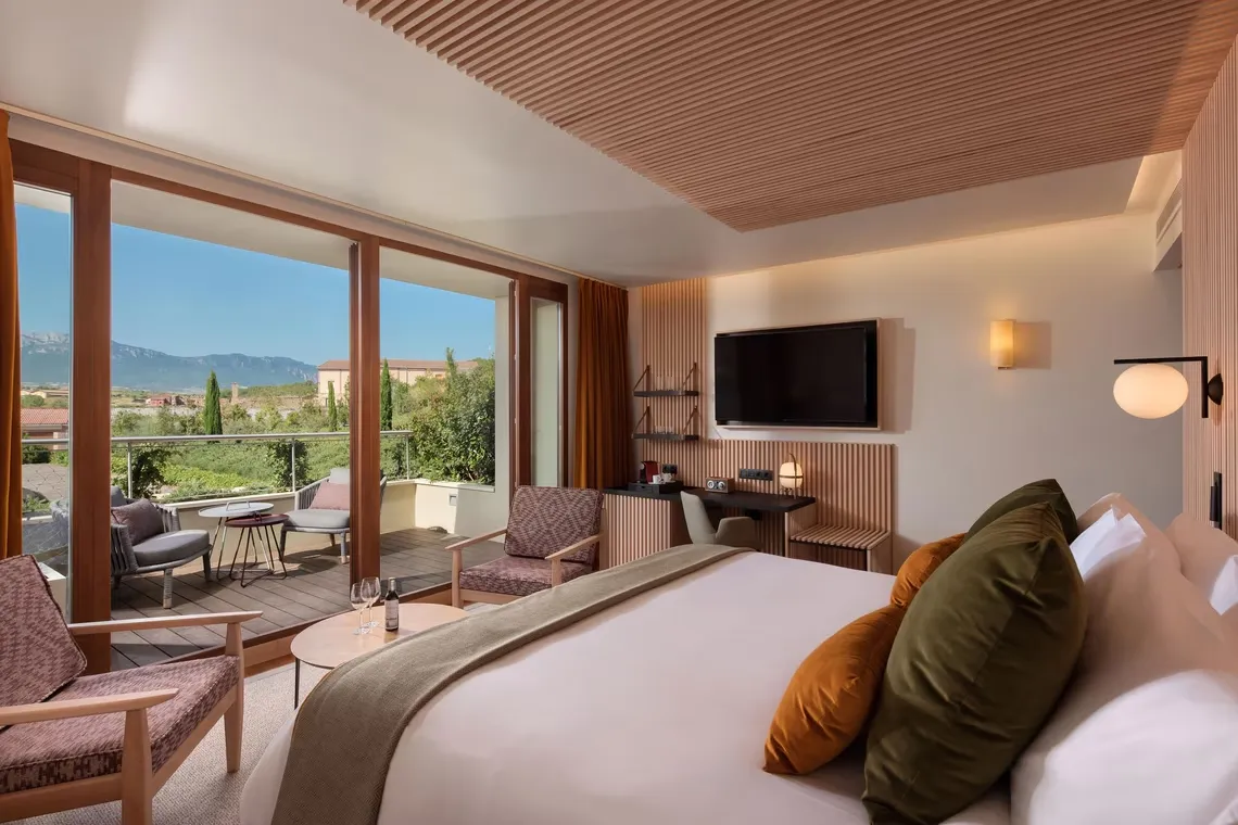 A room in the Spa wing at Hotel Marqués de Riscal, its glass doors open to a terrace over vines and a ridge of mountains